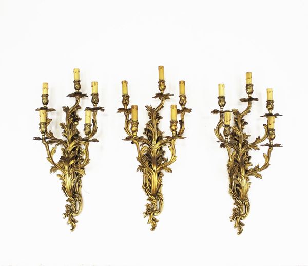 Tre appliques, sec. XX, in bronzo dorato a cinque bracci modellati a guisa di serti fogliati, desinenti in cinque punti luce, alt. cm 67 (3)