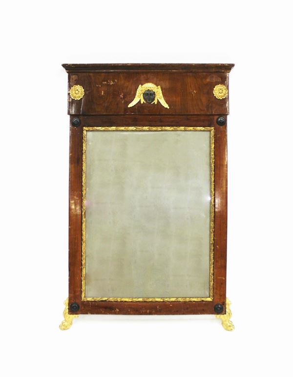Specchiera, Toscana, Impero, lastronata in noce, luce rettangolare, cimasa rettilinea leggermente aggettante sottesa da mascherone di gusto egizio tra rosette scolpite e dorate, cantonali a clipei ebanizzati, piedi ferini, cm 78x119