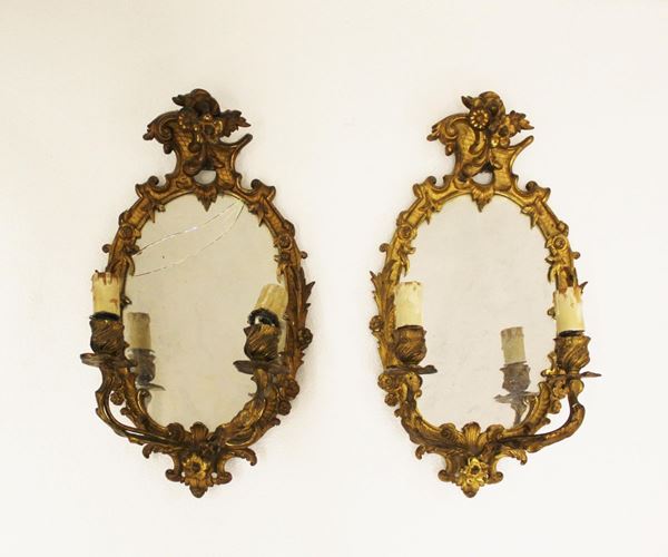 Coppia di ventole con specchiere, sec.XIX/XX, in bronzo dorato e finemente cesellato, cornice ovale percorsa da motivi rocaille fogliati e fioriti, cimasa asimmetrica coppia di bracci desinenti in punto luce, alt. cm 40