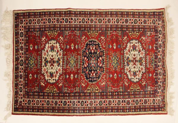 Tappeto, Caucaso, sec. XX, impianto geometrico a tre medaglini centrali, campo nei toni del rosso, cm 253x160                                                                          