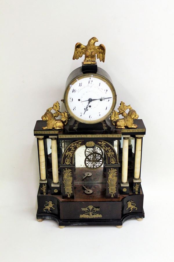 Orologio a pendolo, Ferdinad Ruff Wien, sec. XIX, struttura a tempietto in legno ebanizzato a colonne in alabastro, rapporti bronzei e specchi, quadrante smaltato ad indici arabi tra sculture di leoni accosciati, sormontato da scultura a guisa di aquila imperiale, alt. cm 64&nbsp;&nbsp;&nbsp;&nbsp;&nbsp;&nbsp;&nbsp;&nbsp;&nbsp;&nbsp;&nbsp;&nbsp;&nbsp;&nbsp;&nbsp;&nbsp;&nbsp;&nbsp;&nbsp;&nbsp;&nbsp;&nbsp;&nbsp;&nbsp;&nbsp;&nbsp;&nbsp;&nbsp;&nbsp;&nbsp;&nbsp;&nbsp;&nbsp;&nbsp;&nbsp;&nbsp;&nbsp;