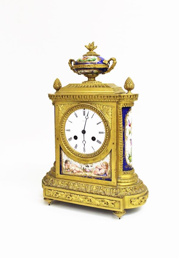 Orologio da tavolo, Parigi, sec. XIX, manifattura Groh&egrave;, in bronzo dorato, impreziosito da placche in porcellana dipinta in policromia a figure di putti e motivi florofaunistici, quadrante smaltato a inci romani, sormontato da elemento decorativo in porcellana di forma vasiforme con motovo a pinnacolo fiammato, alt. cm 37,5