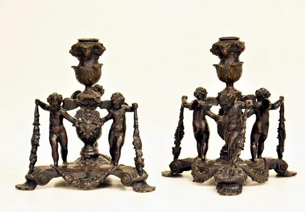 Coppia di candelieri, sec. XX, in ghisa forgiata a guisa di putti, alt. cm
