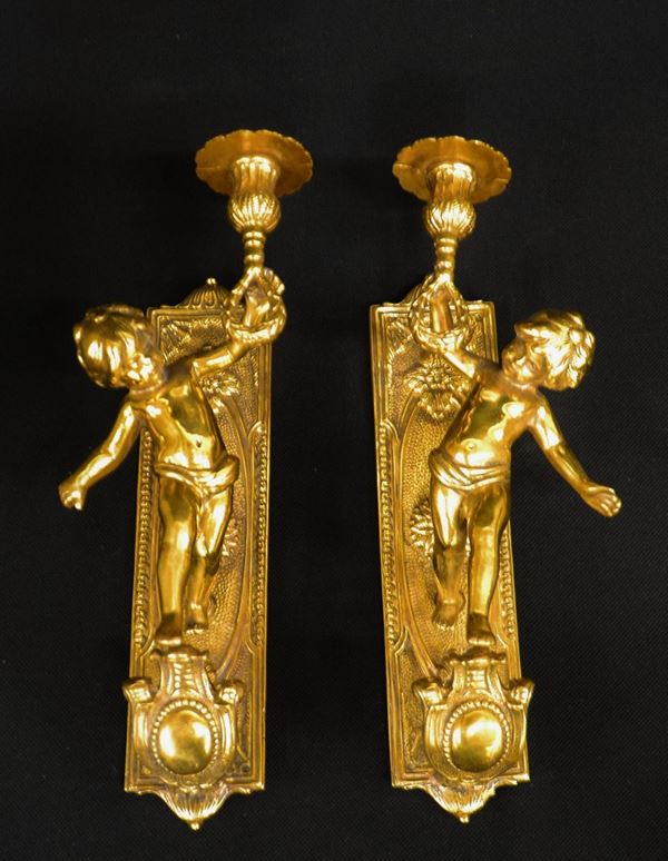 Coppia di applique, sec. XX, in bronzo dorato e forgiato a guisa di putti,