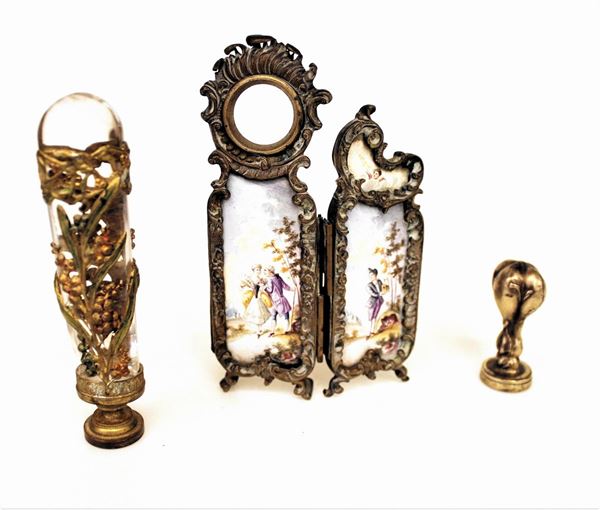 Gruppo di objets de vertu composto da: un paravento in miniatura a due ante con pannelli in smalto policromo con scene settecentesche entro paesaggi, probabilmente mancante di un piccolo orologio; un sigillo con impugnatura in cristallo guarnito da applicazioni in metallo dorato e sbalzato con rami di bacche, inciso con monogramma, danni e un piccolo sigillo quadrilobato con stemma coronato di casa Incontri, seconda met&agrave; secolo XIX, alt. massima cm. 11