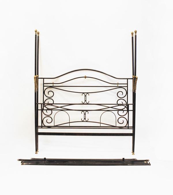 Letto a baldacchino, sec. XX, in ferro battuto laccato, testata e pediera decorati a motivi curvilinei, rapporti mmetallici dorati
