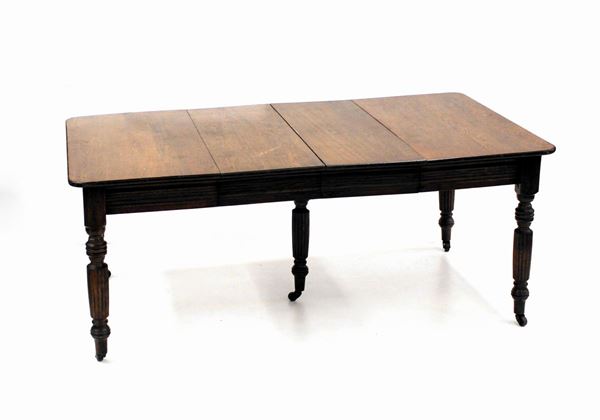 Tavolo, Inghilterra, sec. XIX, in rovere, piano rettangolare allungabile tramite coppia di prolunghe con fasce, cinque gambe tornite desineti su rotelle metalliche, cm 185x107x75, due allunghe da cm 38 cad.&nbsp;