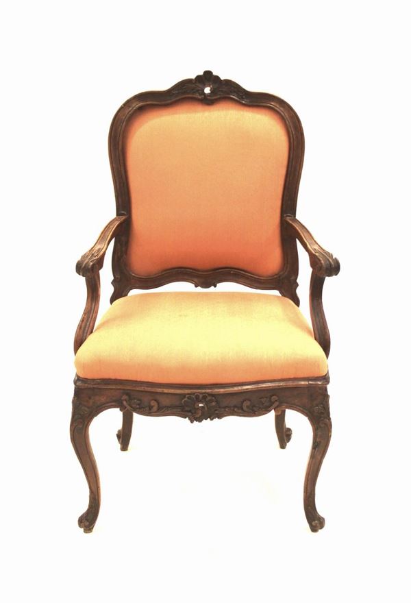 Poltroncina, Veneto, sec. XVIII, in noce, spalliera sagomata a cimasa intagliata a motivo rocaille, motivo che si ripresenta nella fascia, braccioli a giorno desinenti in ricciolo intagliati a motivo fogliato, gambe en cabriole su piede a ricciolo, alt. cm 107
