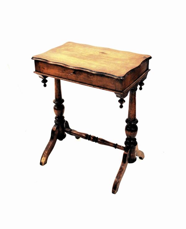 Tavolino da lavoro, sec. XIX, in noce, piano sagomato incernierato, coppia di sostegni torniti su piedi a volute raccordati da traversa, cm 58,5x37,5x72, difetti