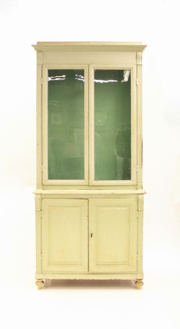 Credenza doppio corpo, sec. XIX, in legno laccato nei toni del verde chiaro, corpo superiore ad ampi sportelli vetrati tra lesene scanalate desinenti in motivo sagomato, elemento decorativo che si ripresenta nel corpo inferiore ad inquadrare coppia di sportelli bugnati, piedi trottola, cm 120x41x265,difetti