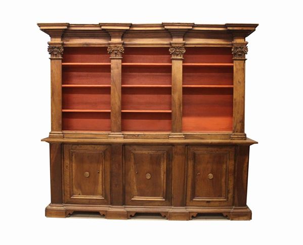 Grande mobile-libreria a tre sportelli, la parte superiore a tre vani sormontati da vari ordini icornici, decorato da lesene piatte con capitelli intagliati con foglie e volute; la parte inferiore pannellata sul fronte, base a cornice su piedi a mensola, elementi dei secoli XVI e XVII assemblati alla fine del secolo XIX/inizio XX