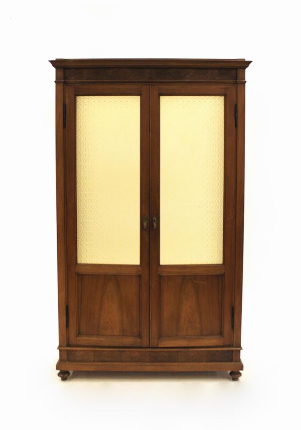 Armadio, sec. XIX, in noce, fronte a due sportelli vetrati nei toni dell&#8217;ambra, interno a ripiani regolabili, cimasa rettilinea modanata, piedi a trottola, cm 125x39x210