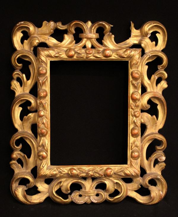 Cornice, sec. XVIII, in legno intagliato e dorato, luce rettangolare percorsa da motivi fruttati, ampia fascia intagliata a flute fogliate contrapposte, ingombro cm 34x40, luce cm 18x24, difetti e mancanze