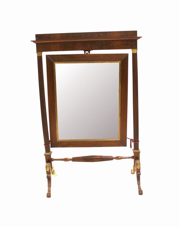 Specchiera, sec. XIX, in noce, luce rettangolare profilata in bronzo, cornice a cannelli ad angolari cordonati, montanti a colonna scannellata desinenti in capitelli bronzei dorati, cimasa rettilinea, traversa tornita centrata da piccolo vano a sezione esagonale, gambe mosse intagliate a riccioli desinenti in piede ferino, cm 99x46x150, difetti
