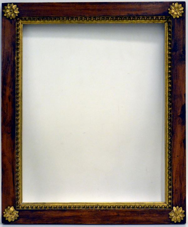 Cornice in stile impero, in mogano parzialmente dorato, battuta liscia su bordo a perline dorate, fascia liscia impreziosita agli angoli da fiori intagliati e dorati; ingombro cm 51,5x43,8, luce cm 41,6x33,8