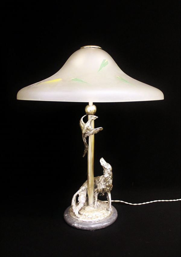 Lampada da tavolo, sec. XX, base in marmo grigio, fusto laminato in argento 800 raffigurante scena di caccia, paralume in vetro satinato, firmato alla base, alt. cm 57