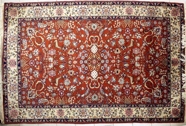 Tappeto, sec. XX, impianto floreale su campo rosso, fascia di bordura nei toni del panna, cm 290x196