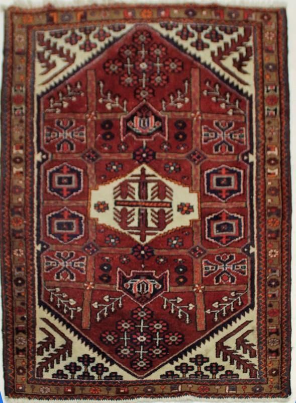 Tappeto, sec. XX, ad impianto geometrico nei toni del rosso, medaglione centrale e cantonali su campo bianco, cm 164x120