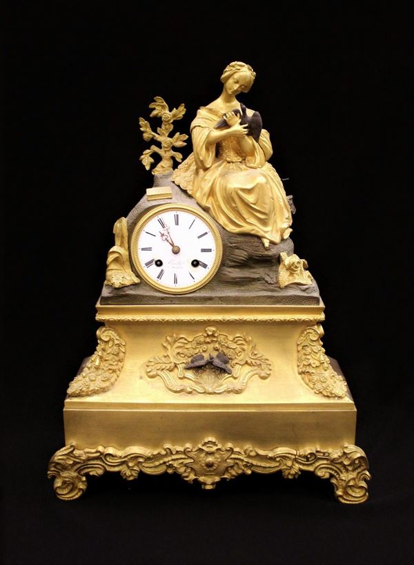 Orologio da tavolo, Francia, sec. XIX, in bronzo brunito e dorato, quadrante smaltato bianco ad indici romani, sormontato da scultura modellata a figura femminile, alt. cm 45