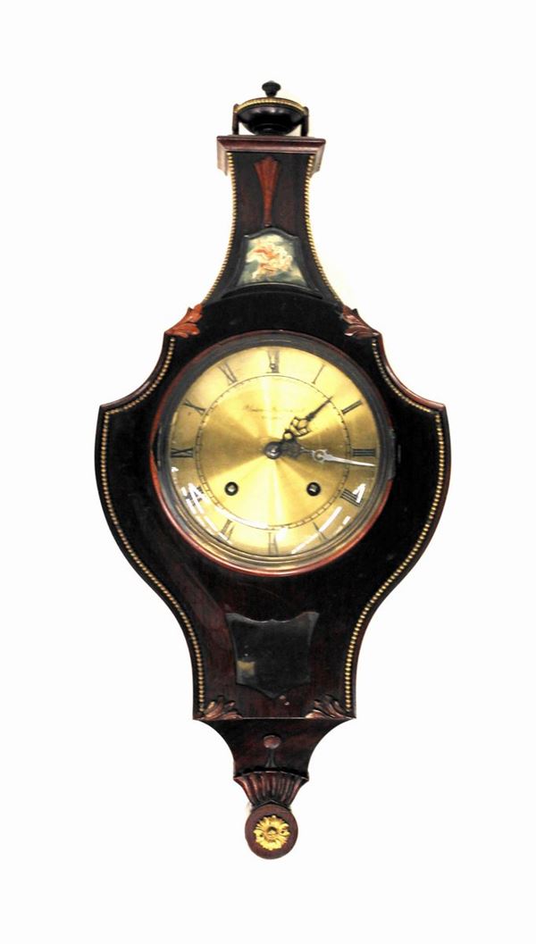 Orologio a muro, primi del sec. XX, di forma sagomata sormontato da motivo a coppa e decorato da cornici perlinate in metallo dorato e pannello in carta dipinta in policromia con figura su Pegaso, quadrante iscritto: Union Sti&atilde;rnsund Sweden, alt. cm. 64,