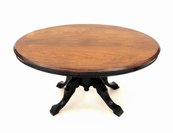 Tavolino, sec. XIX, in mogano, piano ovale, fusto centrale tra quattro colonnine tornite desinenti su sostegni mossi e intagliati cm 120x89x58