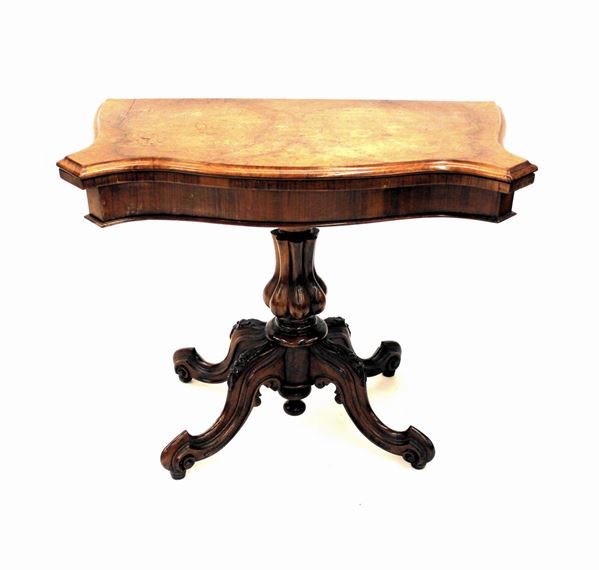 Tavolino da gioco, sec. XIX, piano sagomato incernierato a libro, fusto centrale tornito a sezione polilobata su quattro sostegni mossi intagliati e decorati a motivi fitomorfi desinenti su rotelle, cm 94x47x73