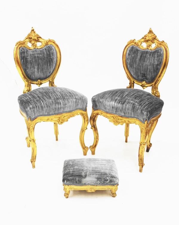 Coppia di sedie, sec. XIX, in legno intagliato e dorato, schienale sagomato, cimasa centrata da motivo asimmetrico fortemente intagliato, rivestite in velluto nei toni del celeste, gambe mosse; piccolo poggiapiedi en suite, alt. cm 95, difetti (3)