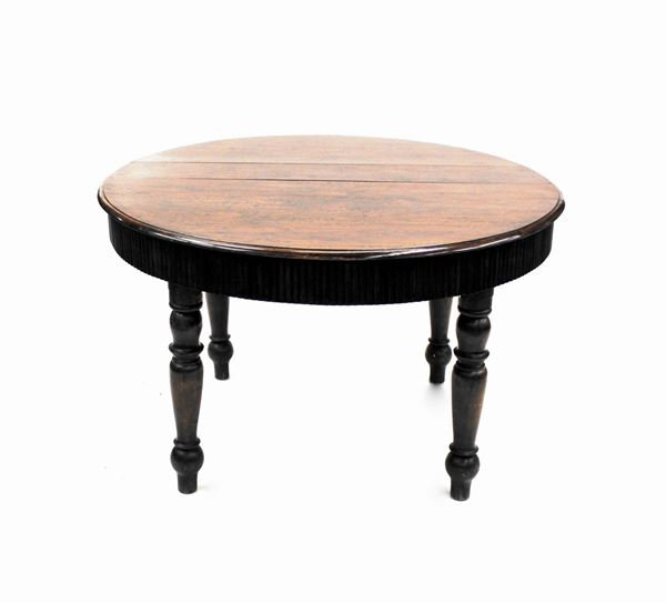 Tavolo allungabile, sec. XIX, in noce, piano circolare sotteso da fascia modanata a semi cannelli, gambe tornite, diam. cm130, alt. cm 79, pi&ugrave; due prolunghe di epoca posteriore di cm 75 e cm 40