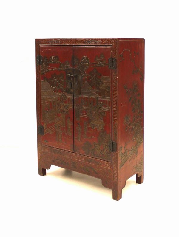 Stipo, Cina, sec. XX, in legno laccato nei toni del rosso e decorato a figure e paesaggi in rilievo, fronte a due sportelli, piedi a plinto, cm 87x41,5x122,5