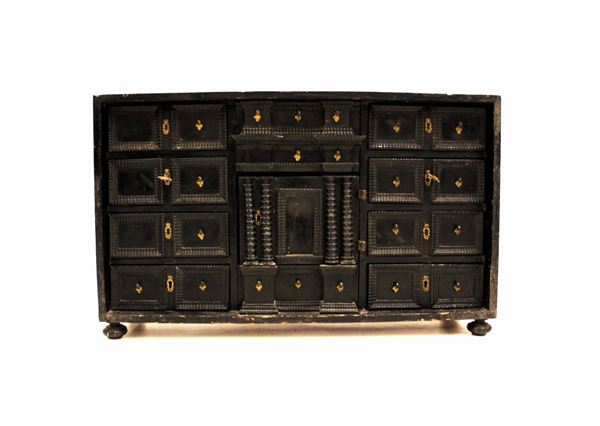 Stipo monetiere, sec. XVIII, in legno ebanizzato, fronte a numerosi tiretti centrati da sportello di gusto architettonico, piedi a sfera schiacciata, cm 85x26x51,5, mancanze, modifiche e restauri                                                       