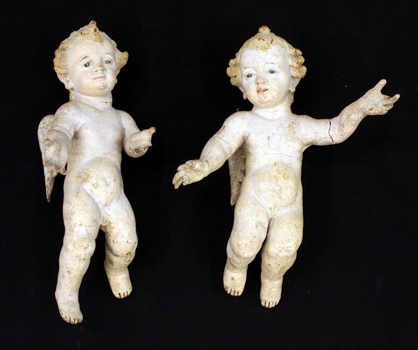 Coppia di putti alati, sec. XVIII, in legno scolpito e laccato, occhi in pasta vitrea, alt. cm 40 (2)  