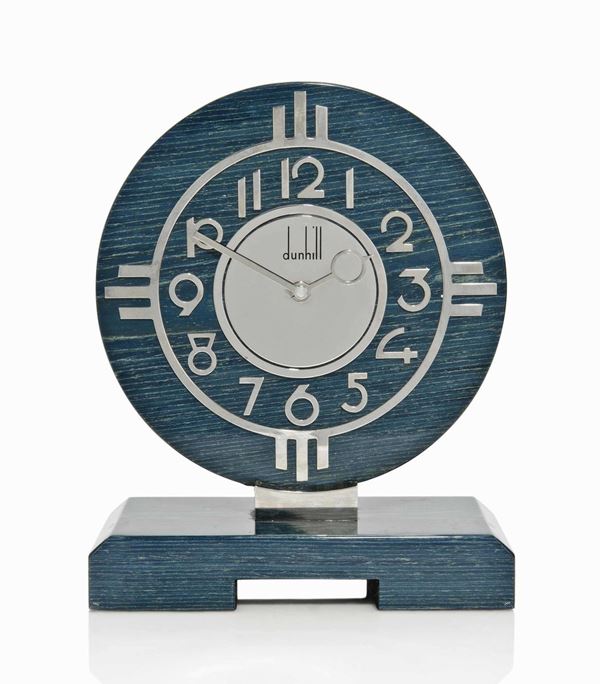Orologio da tavolo, Alfred Dunhill, Londra, fine sec. XX, in legno laminato in stile art-deco, con numeri arabi cromati, dunhill firmato al centro del quadrante, movimento al quarzo francese, completo di garanzia, cm 21,5x10x27,5, difetti