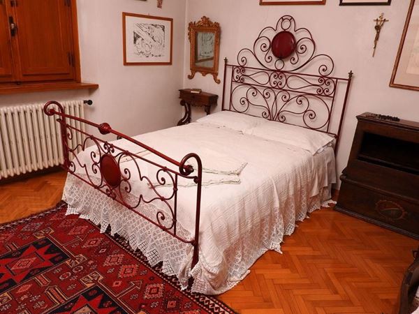 Letto, sec. XIX, in ferro battuto laccato bordeaux, schienale e finale    