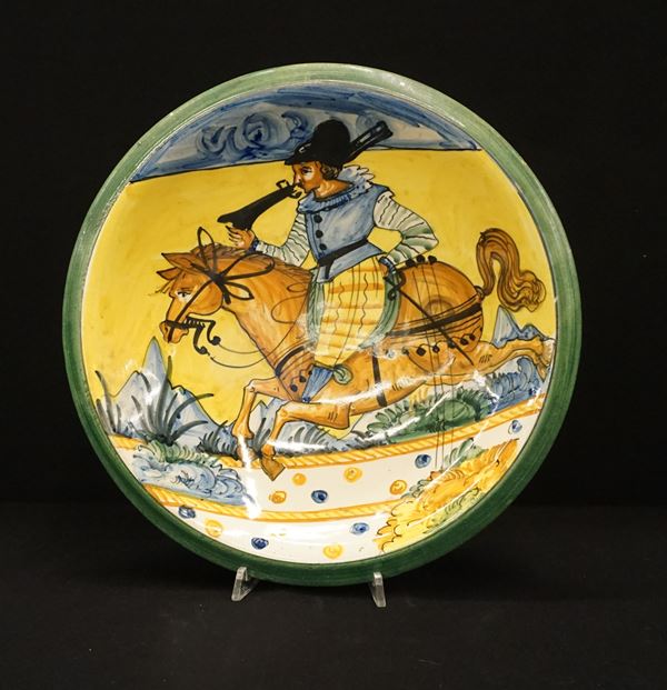 



Piatto da parete, Montelupo, sec. XIX, in maiolica dipinta in policromia raffigurante cavaliere con archibugio, diam. cm 32