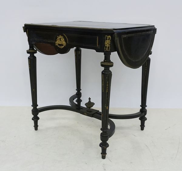 



Tavolino, in stile Boulle, sec. XIX, in legno laccato nero con intarsi in metallo dorato, un cassetto, gambe scanalate riunite da traversa, alette laterali, in cm 70x57x74