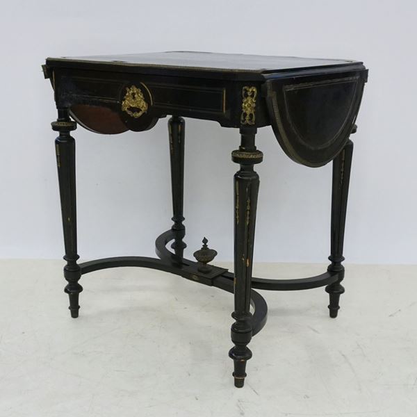 



Tavolino, in stile Boulle, sec. XIX, in legno laccato nero con intarsi in metallo dorato, un cassetto, gambe scanalate riunite da traversa, alette laterali, in cm 70x57x74
